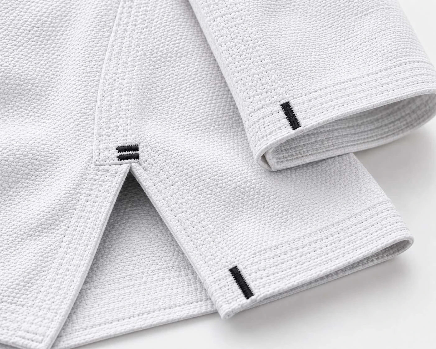 Close-up of bar-tacked cuffs and skirt on a white BJJ gi